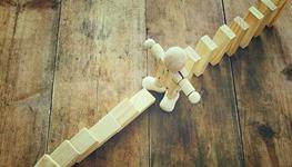 Wooden figure stopping falling dominos
